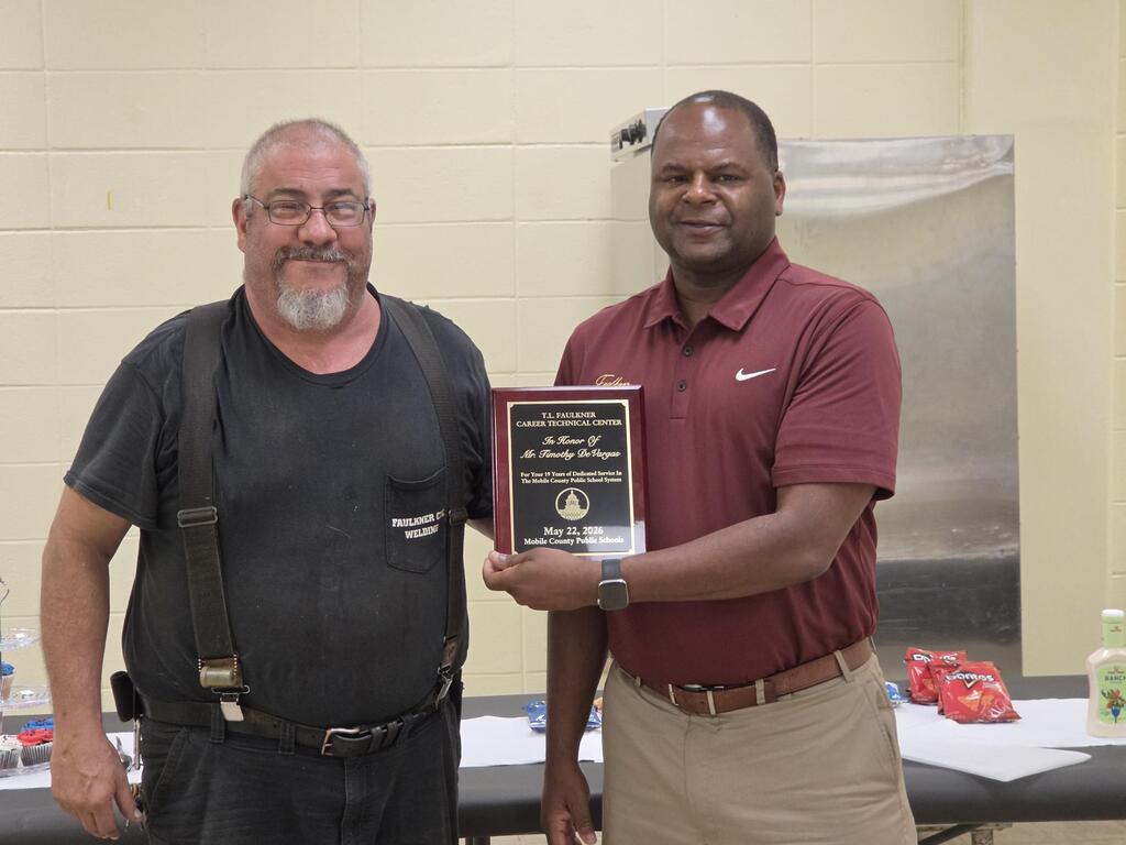 Welding Instructor and Principal holding retirement plaque.