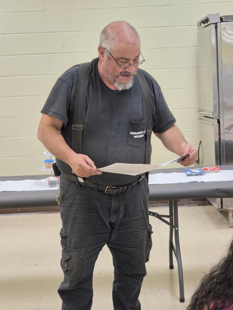 welding instructor holding retirement card