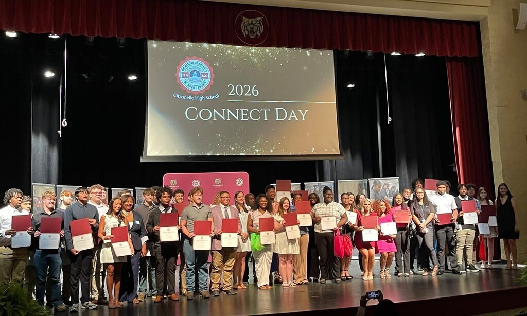 A large group of Citronelle High students holding certificates on a stage