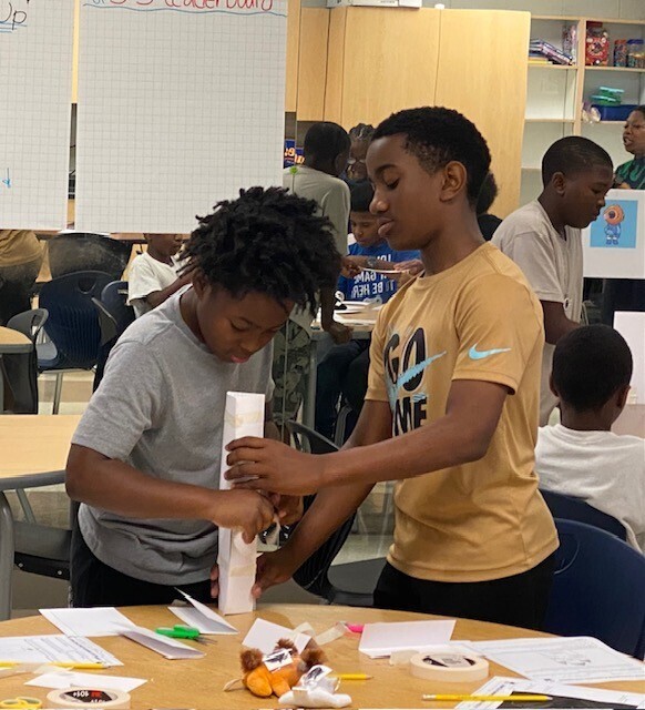 Two boys construct a tower made of paper