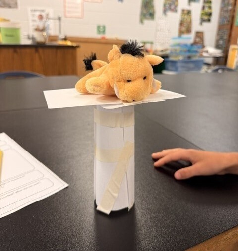 A stuffed animal sits atop a paper tower