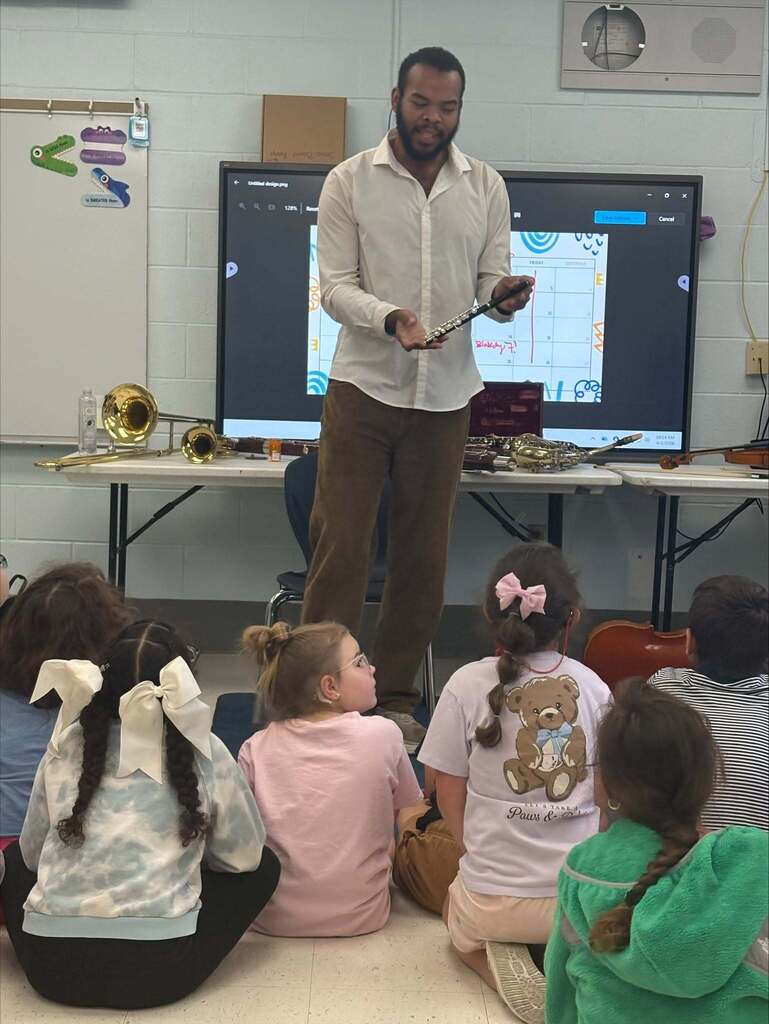 A man shows a piccolo to a group of students