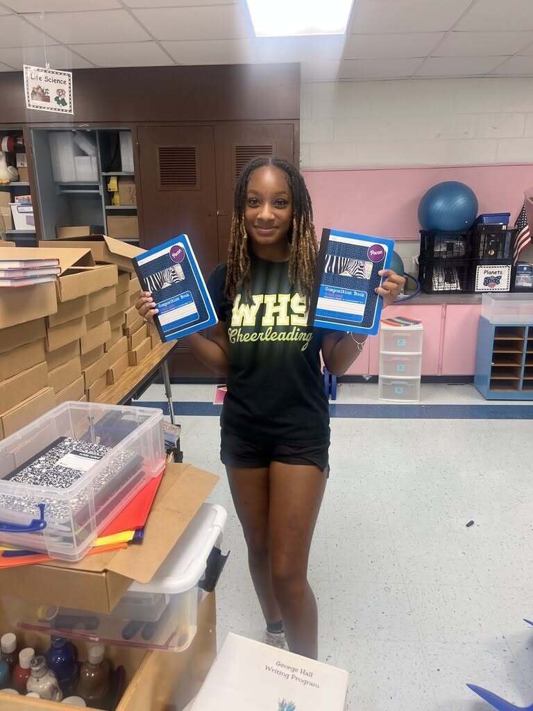 A Williamson cheerleader holds two notebooks with pictures of zebras on them