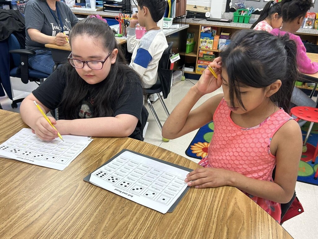 Two students writing on worksheets at a table