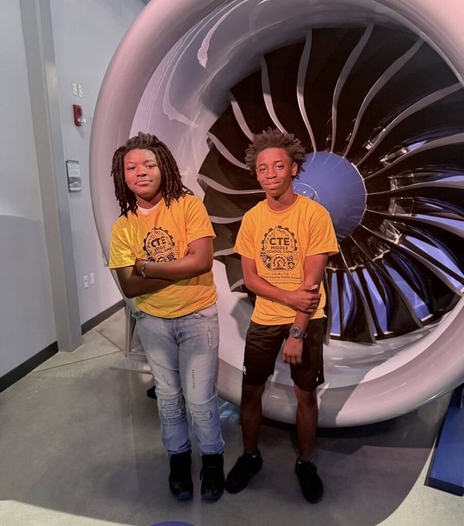 Two students stand in front of a model of a jet engine