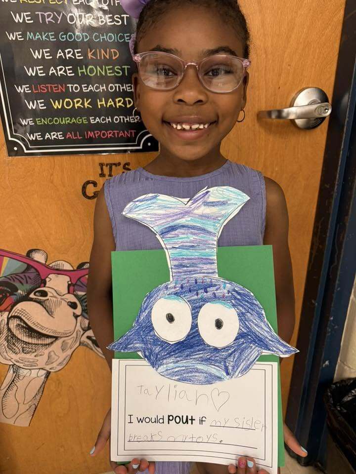 A girl holds her artwork of a fish