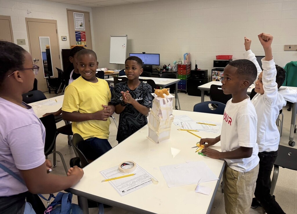Elementary students celebrating after building a paper tower that can support a stuffed animal