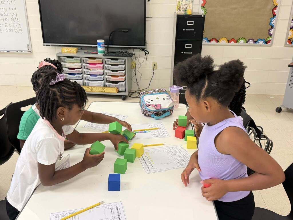Students at a table using foam blocks as math manipulatives