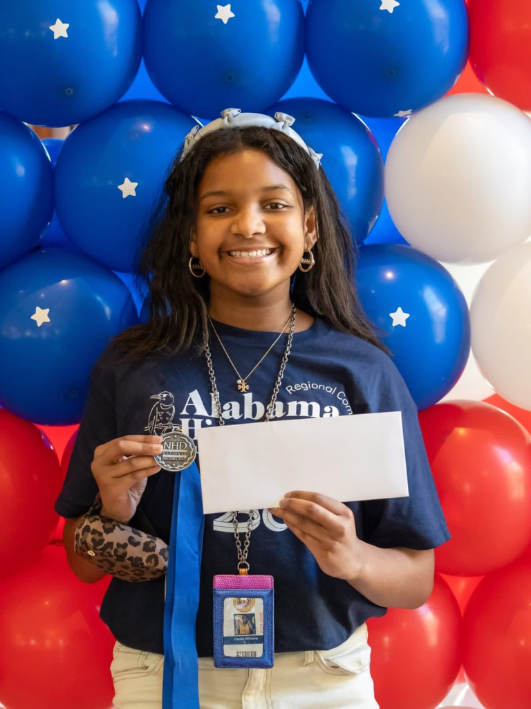 Cassie Williams, holding an envelope and a medal
