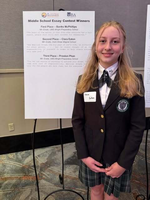 Clara Eaton stands beside a placard with the names of winners in the Law Day Essay Contest