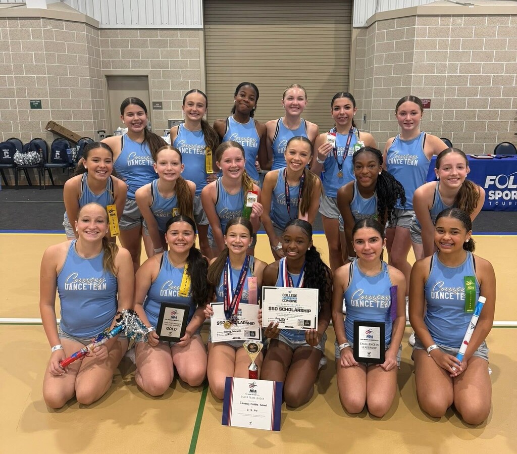 The Causey Middle School dance team, with medals, certificates, spirit sticks and a trophy, in a gymnasium
