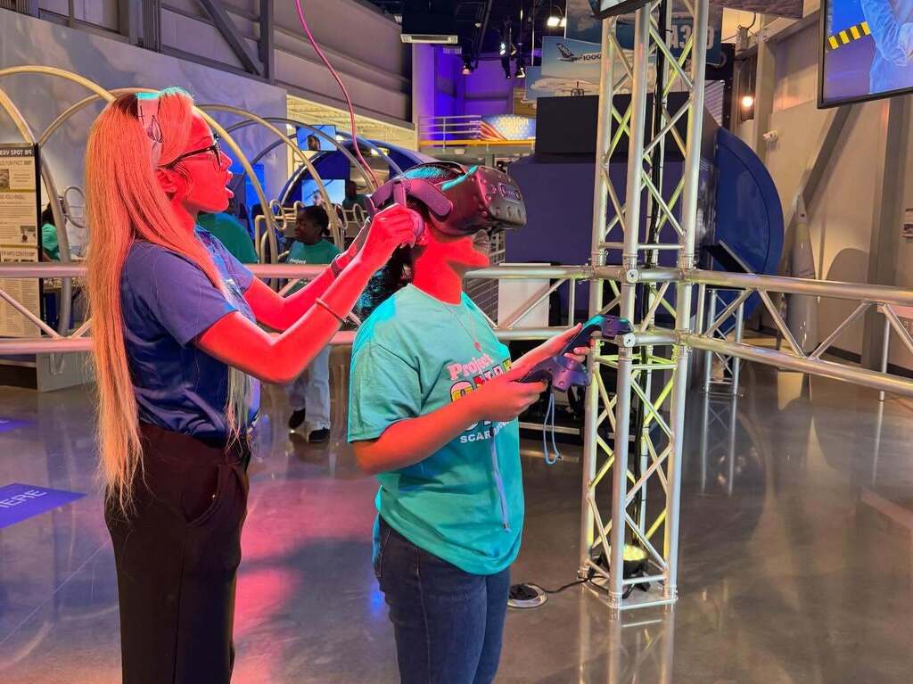 A Flight Works Alabama staff member helping a student use VR goggles