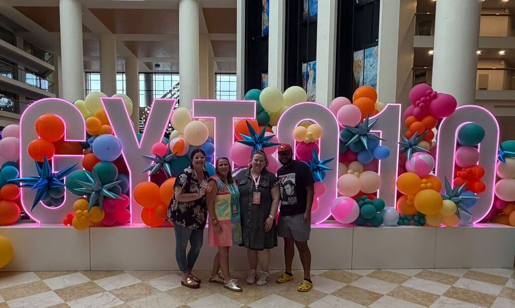 Four educators stand in front of tall letters that spell "GYTO 10"