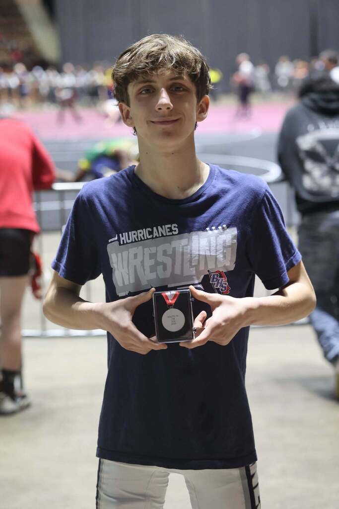 Tres Watson, wearing a Hurricanes Wrestling T-shirt and holding a medal