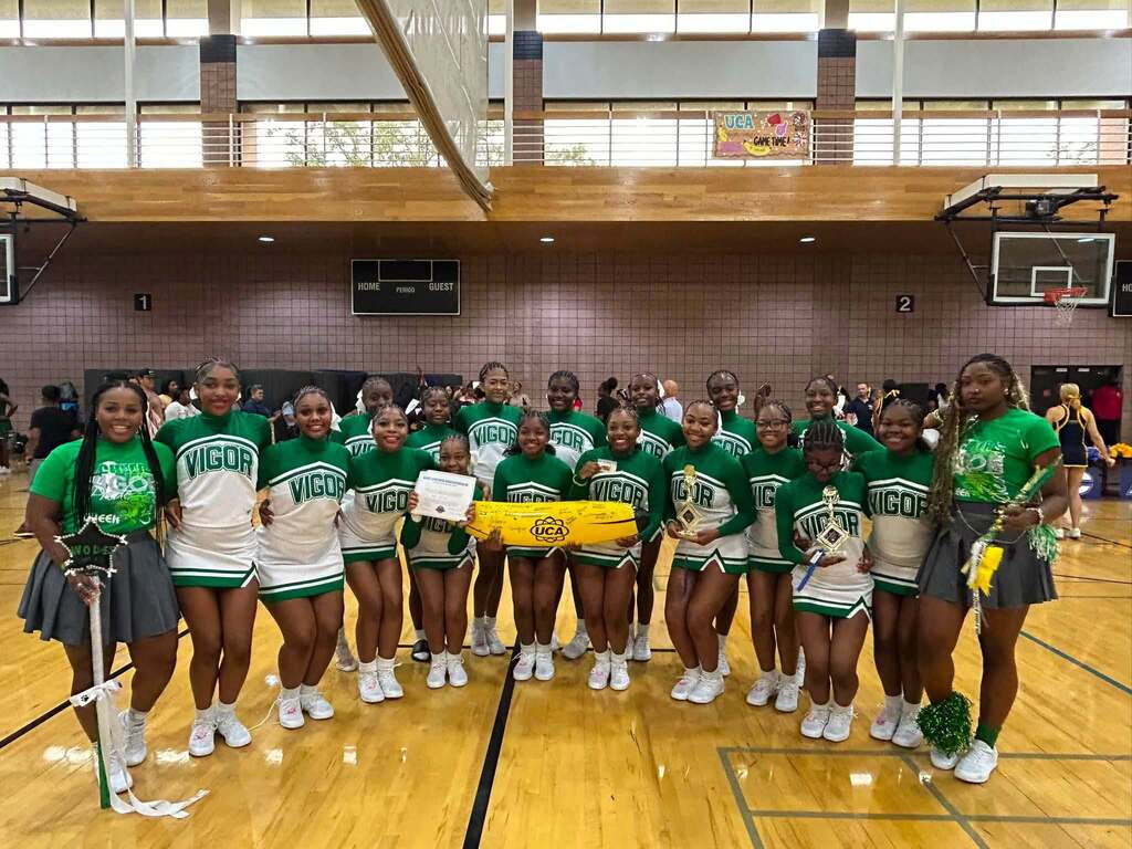 The Vigor cheerleaders in a gymnasium, holding trophies and an inflatable banana
