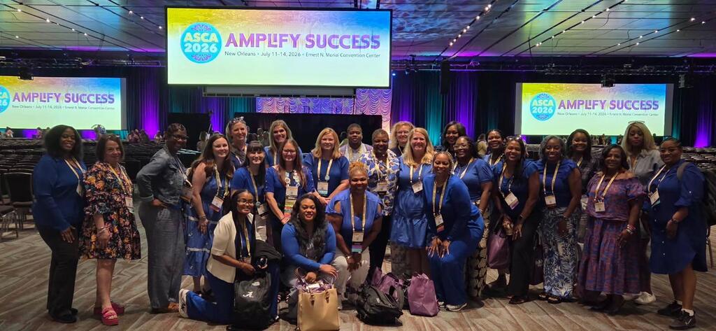 A large group of school counselors at a conference, wearing lanyards