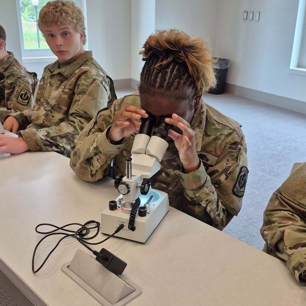 A JROTC cadet looking into a microscope