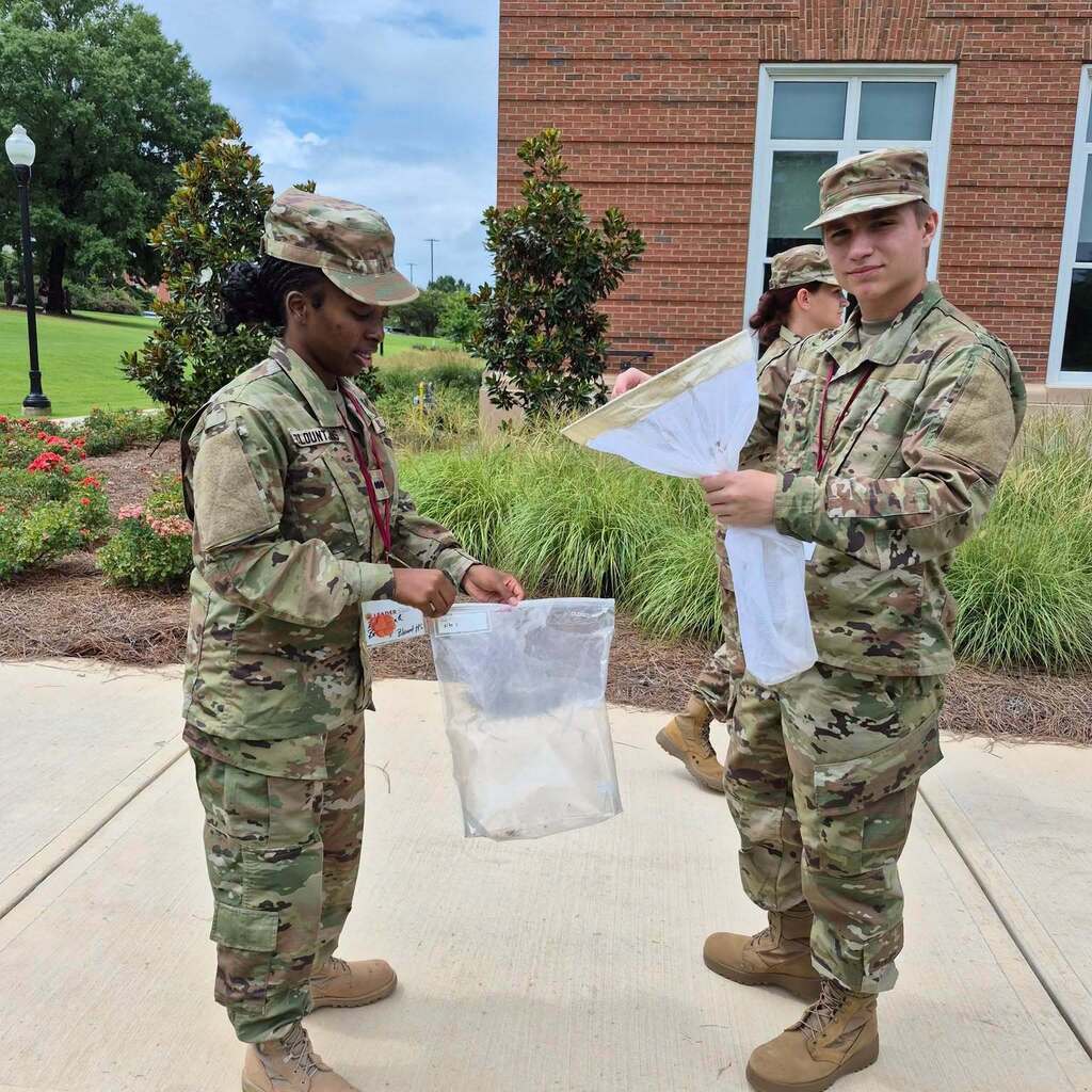 Two JROTC cadets holding plastic bags partially filled with water