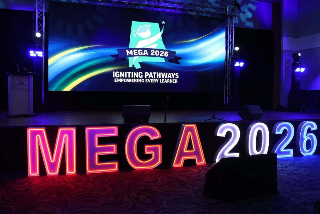 A darkened stage with lit letters reading MEGA 2026
