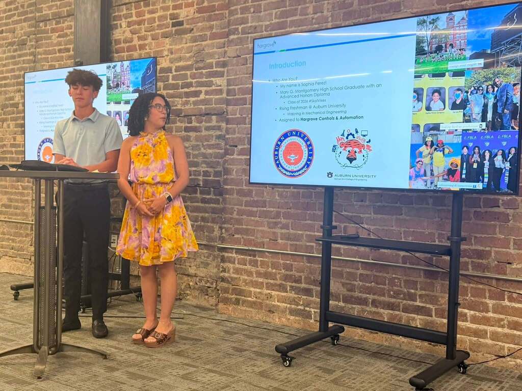 Two high school students standing at a podium in front of a smartboard