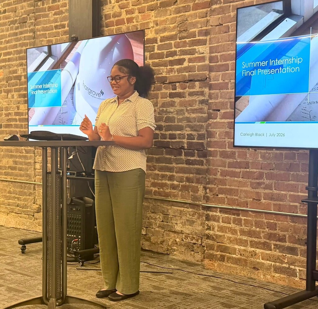 A high school student standing at a podium in front of a smartboard