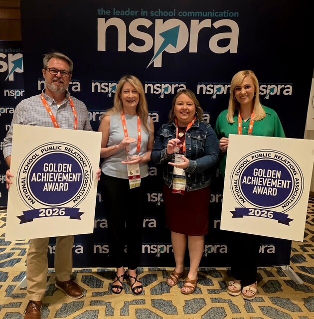 Four communications professionals holding awards and signs reading "Golden Achievement Award"