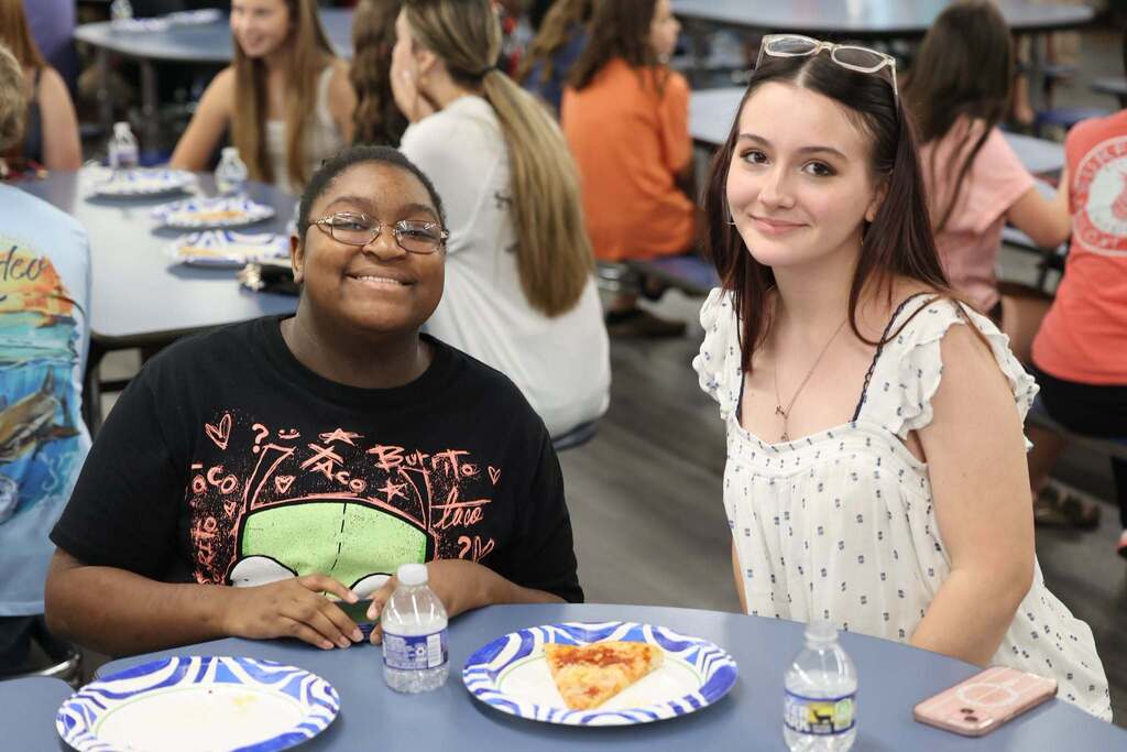 Two students at a table, with pizza and water in front of them