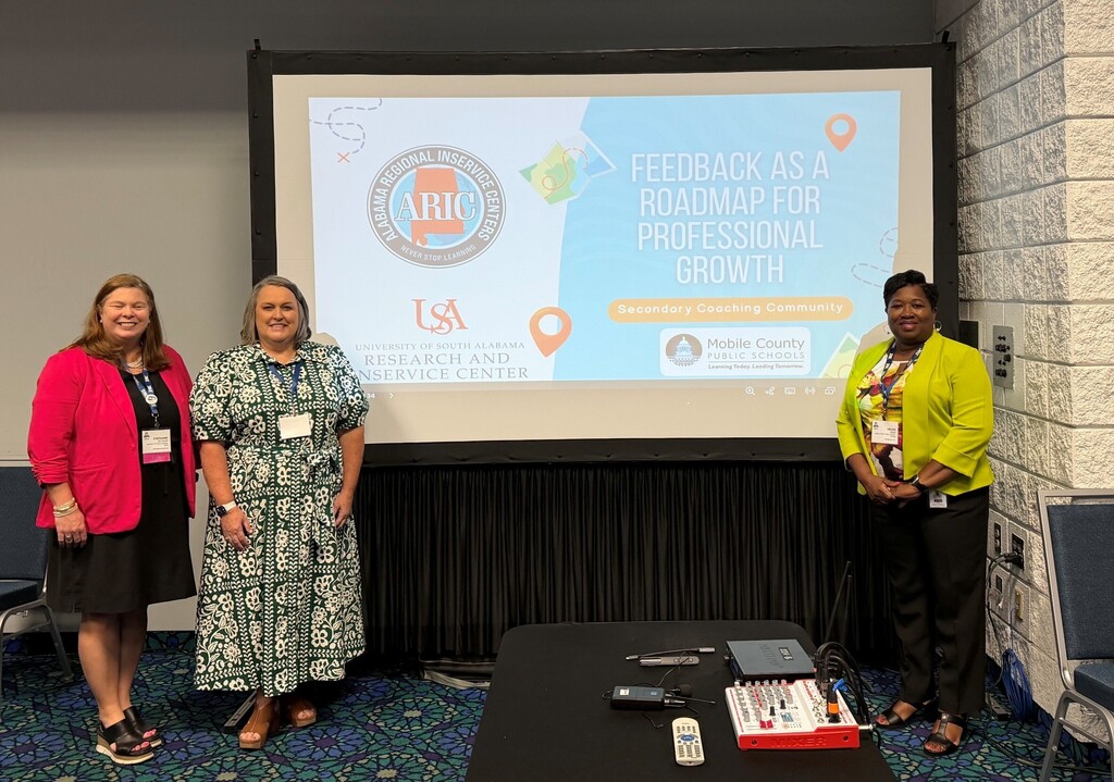 Three women standing in front of a smartboard that reads "Feedback as a Road Map for Professional Growth"
