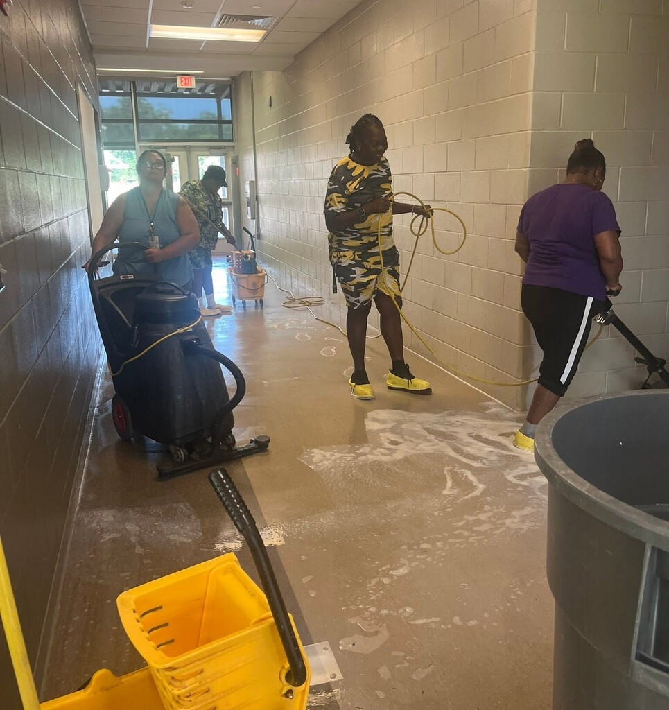 Custodians cleaning the floors in a school hallway