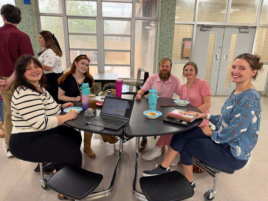 A group of teachers seated around a cafeteria table