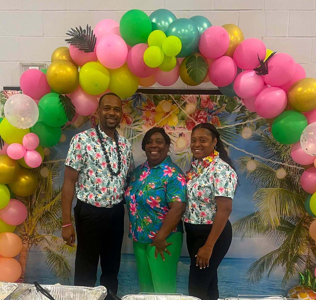 A principal and two assistant principals in Hawaiian shirts and leis