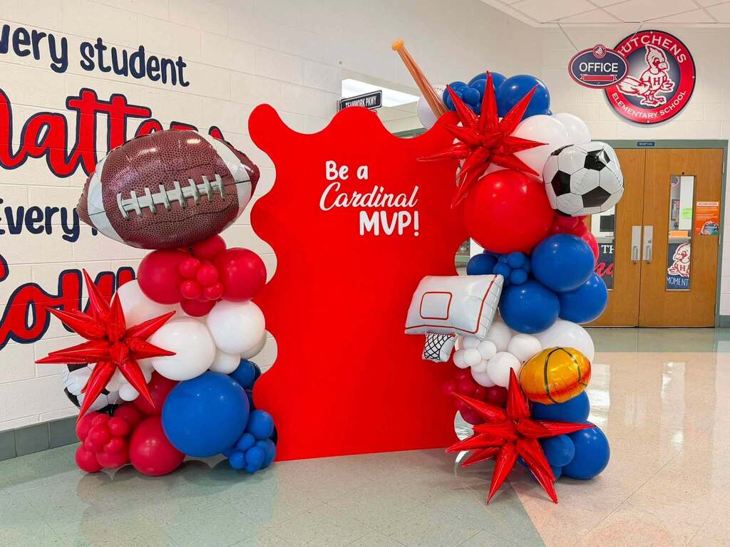 A display with footballs and basketballs that reads "Be a Cardinal MVP"