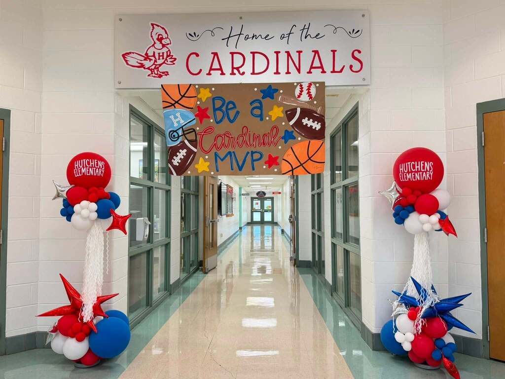 A school hallway with banners that read "Home of the Cardinals" and "Be a Cardinal MVP"
