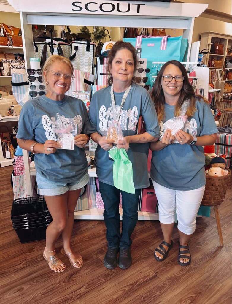 Three teachers inside a boutique, holding treats