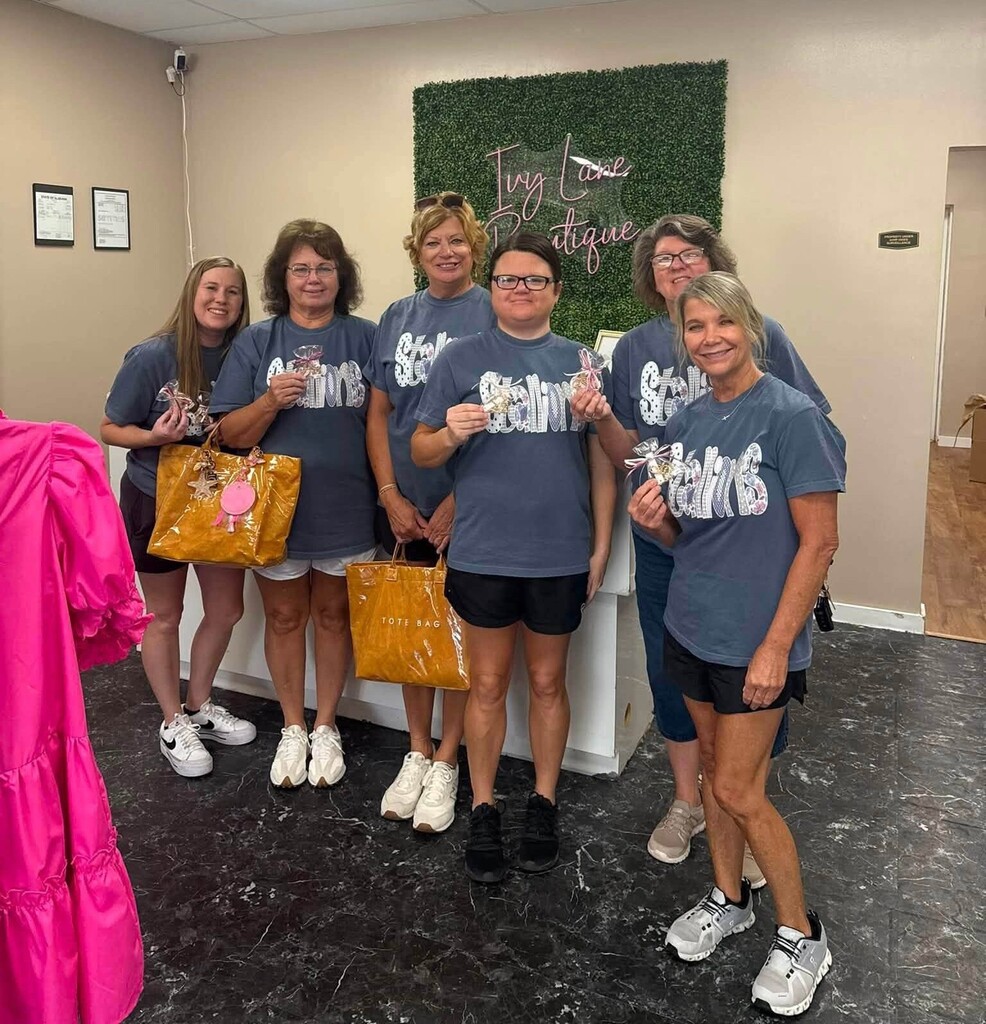 Six teachers standing in a boutique, holding shopping bags and small treats