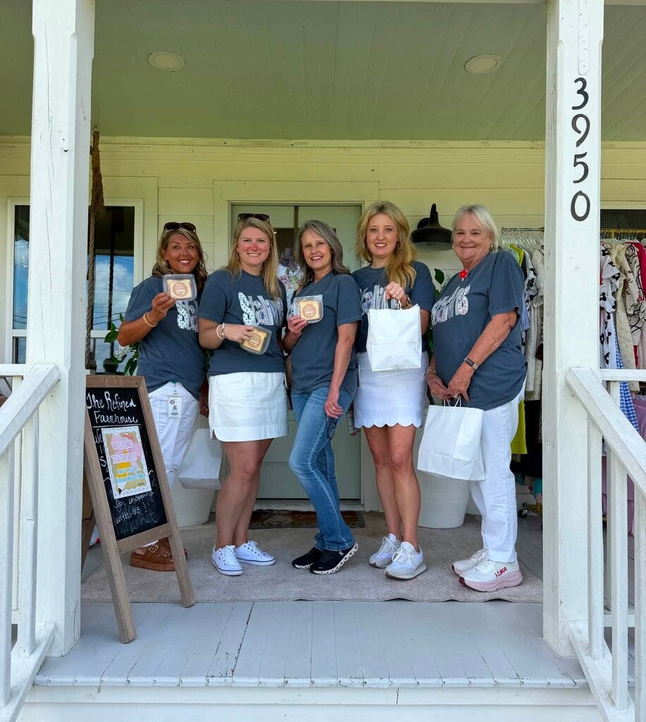Five teachers on the steps of a shop, holding treats and shopping bags