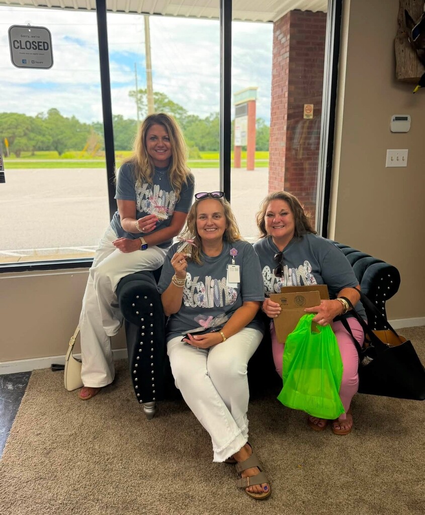 Three educators holding up small snacks in a boutique