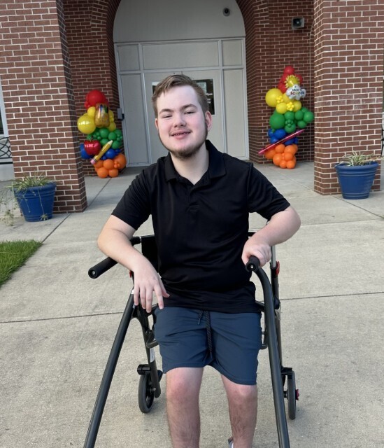 Student in front of the school smiling in-between balloon decorations