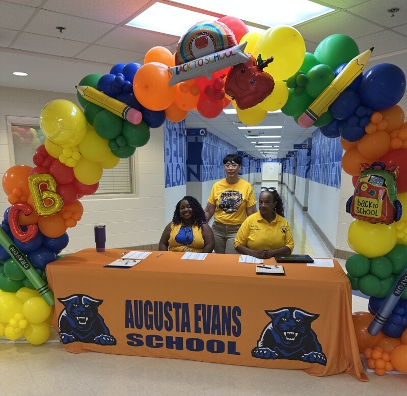 Mrs. Kidd and two other staff members under the balloon arc getting ready for Meet the Teacher