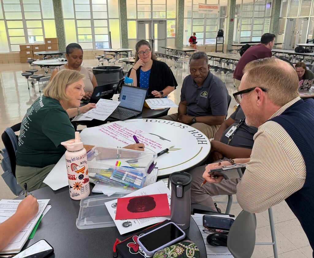 Teachers seated around a table, writing down goals