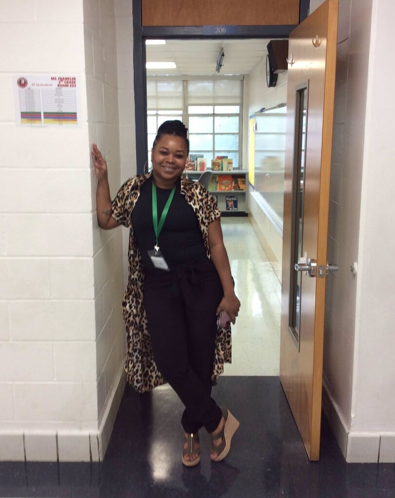 A teacher stands in a classroom doorway