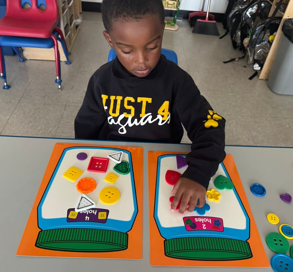 Child in a sitting at a table, playing with an educational game.