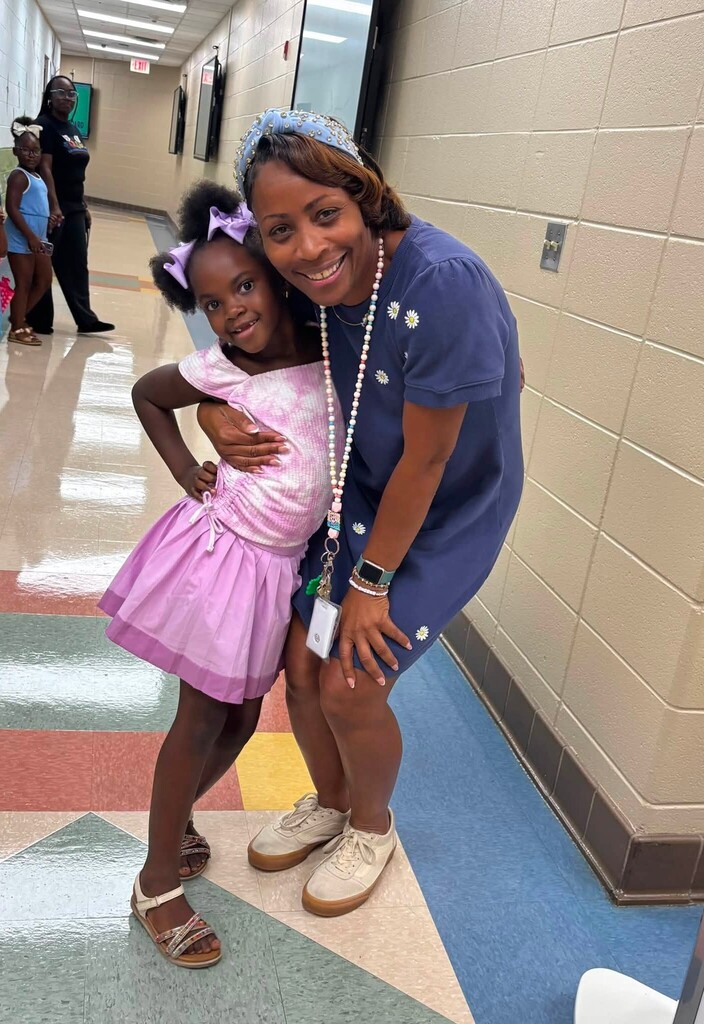 A teacher hugging a student in a hallway