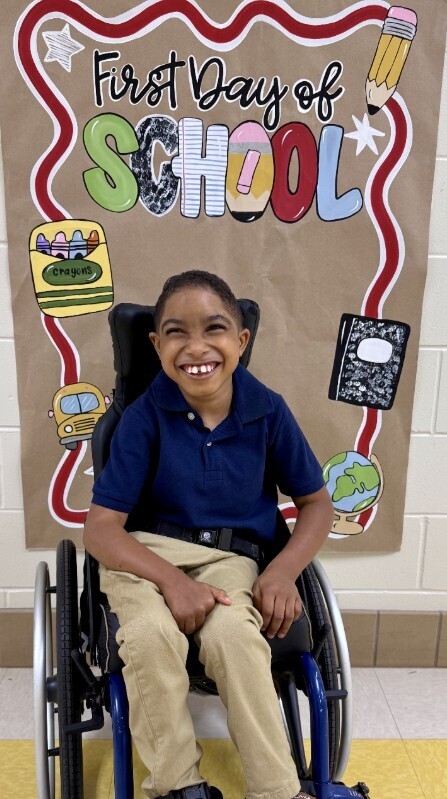 Cub level student smiling in front of first day of school sign
