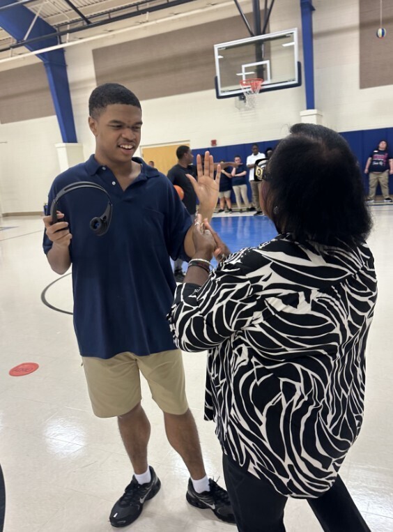 Para and giving student a high five in the gym on the first day of school