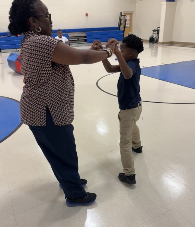 Para with cub level student dancing in the gym during PE