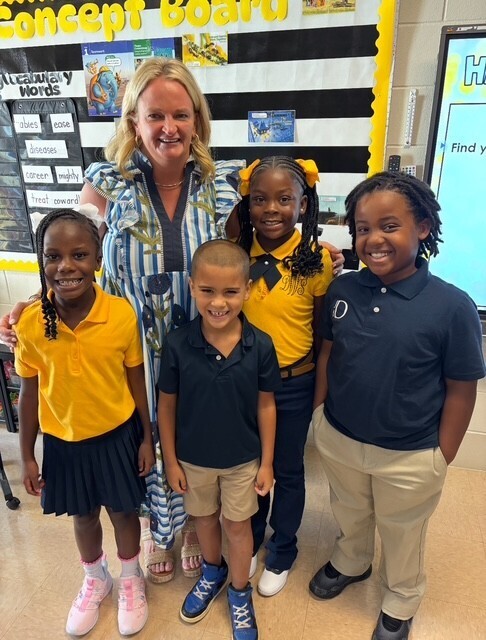 Taylor-White Principal Sonia Andrews stands with four students