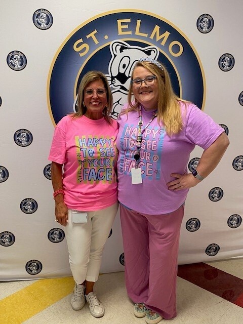 Two teachers stand in front of a St. Elmo Elementary banner