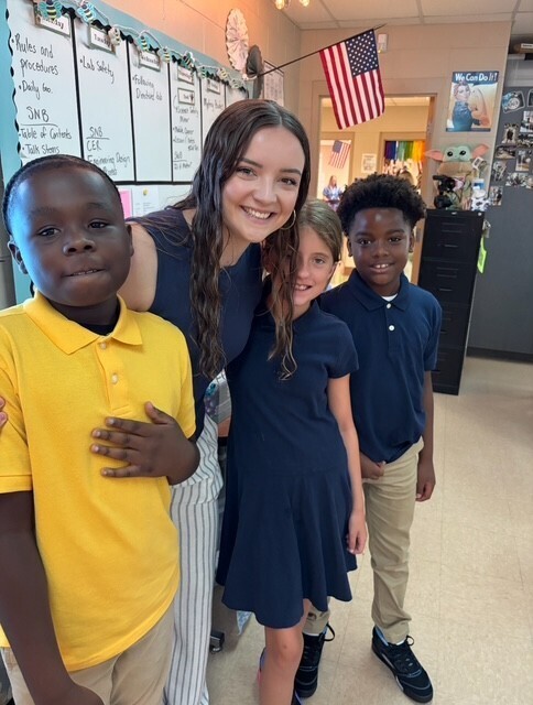A teacher stands with three students