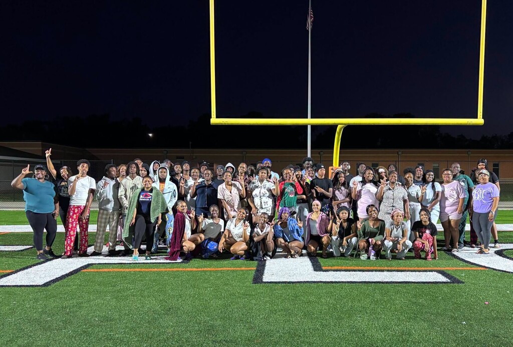 A large gathering of students in a group photo on a football field